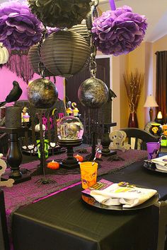 the table is decorated with purple flowers and black candlesticks for halloween party decorations