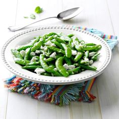 a white bowl filled with green beans and feta cheese on top of a table