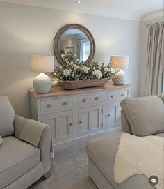 a living room filled with furniture and a large mirror on top of a dresser next to a window