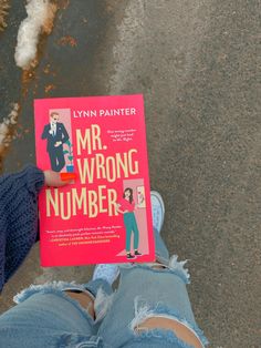 a person holding up a book about mr wrong number on the street in front of them