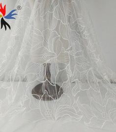 a white sheer fabric with flowers and leaves on the bottom is shown in front of a mannequin's head