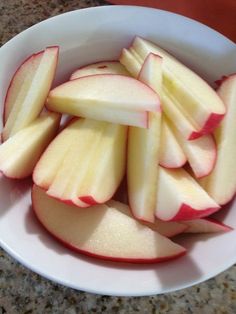 sliced apples are in a white bowl on a counter top, ready to be eaten