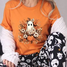 Retro Ghost T-shirt, Vintage Floral Ghost Halloween T-shirt, Flower Halloween Shirt, Cute Ghost Shirt, Retro Fall Shirt, Vintage Ghost Tee Welcome to NoordesignBySelin!🌟 Thank you for visiting our shop! We hope you find something that adds a little extra warmth and beauty to your day. 😊 Happy Shopping! 🛒 📢 Important Details: Check All Photos: Review all images for product details. 📸 Choose Size & Color: Select your T-shirt size from the drop-down list next to the item picture. For color opt Spooky Orange T-shirt For Fall, Spooky Orange Cotton T-shirt, Orange Halloween T-shirt With Funny Print, Halloween Funny Print Orange T-shirt, Spooky Short Sleeve Orange Shirt, Orange Funny Print T-shirt For Halloween, Spooky Orange Crew Neck T-shirt, Halloween Orange T-shirt With Cartoon Print, Orange Halloween T-shirt With Cartoon Print