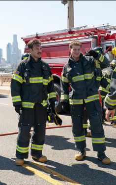 two firefighters standing next to each other in front of a fire truck