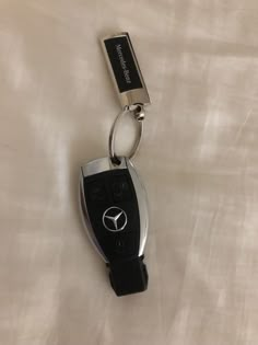 a mercedes keychain with a black and silver logo on it's side