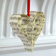 a heart shaped ornament hanging from a red string with sheet music notes on it