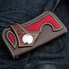 a red and brown wallet sitting on the back of someone's blue jean pants