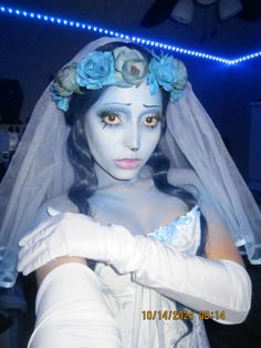 a woman with white makeup and blue flowers on her head is dressed up as a corpse bride