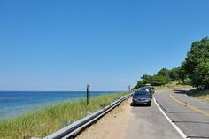 the car is driving down the road by the water