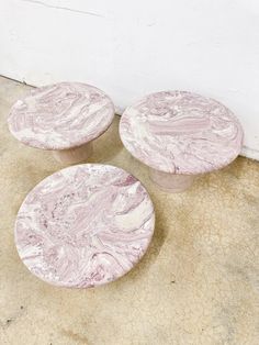 three pink marbled tables sitting on the ground