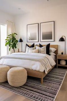 a bedroom with white walls and wood floors has a large bed surrounded by two planters