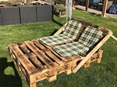 a couch made out of wooden pallets sitting on top of green grass next to a building