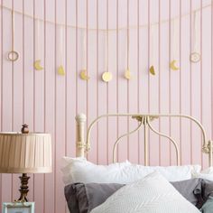 a bedroom with pink walls and white bedding has gold circles hanging above the headboard