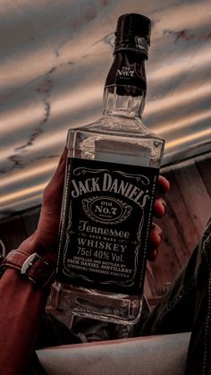 a person holding up a bottle of jack daniels whiskey