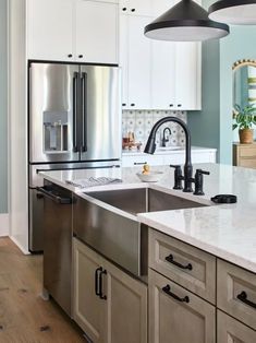 a large kitchen with stainless steel appliances and white marble counter tops, along with wooden flooring