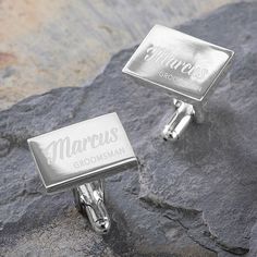 two silver cufflinks with the word mum engraved on them sitting on some rocks