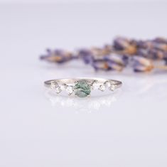 a close up of a ring on a table with lavender flowers in the foreground