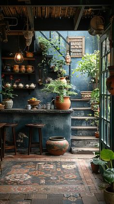 a room filled with lots of potted plants next to a kitchen counter and stairs