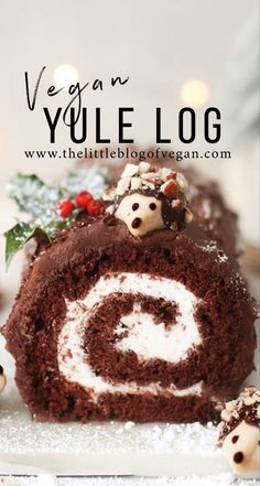 a chocolate cake roll with white frosting and christmas decorations on top, in front of the words vegan yule log