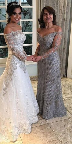 two women standing next to each other in formal wear, one holding the hand of another woman