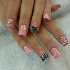 a woman's hand with pink and black nail polishes on her nails, which are decorated with bowknots