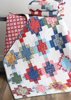 two quilts stacked on top of each other in the middle of a room with wood flooring