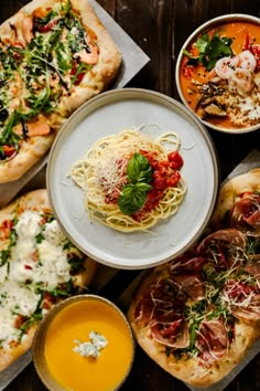 several different types of food are on the table, including pizzas and soups