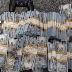 a pile of money sitting on top of a carpet next to a video game controller