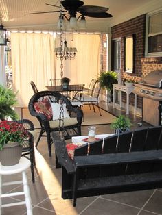 an outdoor living area with patio furniture and potted plants on the side of the porch