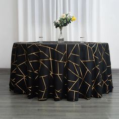 a black table cloth with gold lines on it and a vase filled with yellow flowers