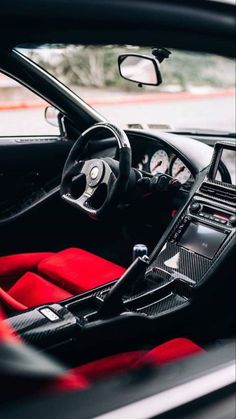 the interior of a sports car with red carpet and black leather seats, steering wheel and dash board