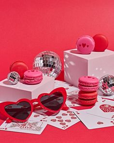 pink macaroons, heart - shaped sunglasses and disco balls on red background