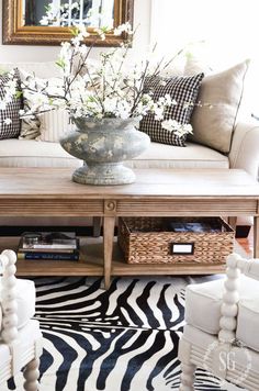 a living room with zebra print rugs and pillows on the floor, in front of a