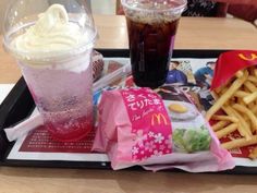 a tray that has some food on it and drinks in plastic cups next to each other