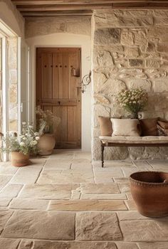 a stone house with potted plants and a bench in the entryway to it