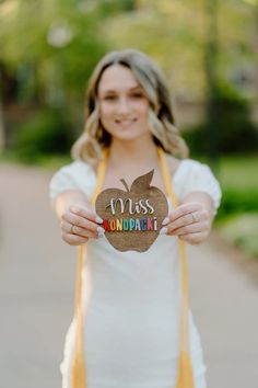 a woman holding up a paper apple with the word miss on it