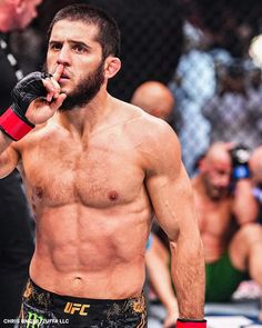 a man with no shirt on standing in front of a crowd holding a red boxing glove