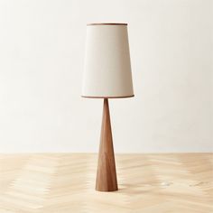 a table lamp with a white shade on it sitting on top of a wooden floor