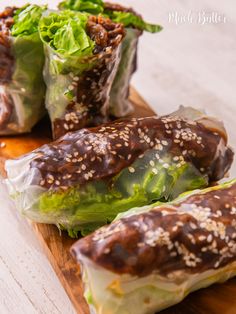 lettuce wrapped in sesame seeds on a cutting board with another wrapper full of lettuce