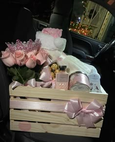 a wooden crate filled with pink roses and other items in the back of a car