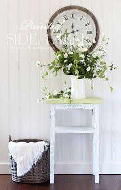 a white table with flowers and a clock on the wall