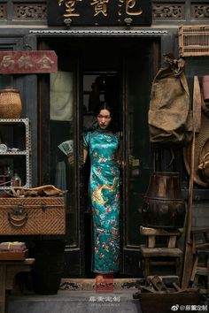 a woman standing in an open doorway with her hands on her hips wearing a green dress