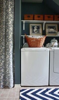 a washer and dryer in a laundry room with blue walls, patterned rugs and pictures on the wall