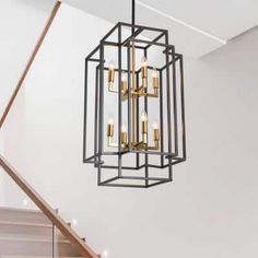 a chandelier hanging from the ceiling in a room with white walls and stairs