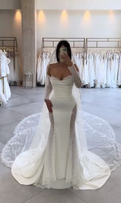 a woman is taking a selfie in her wedding dress while wearing a long sleeved gown