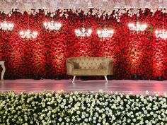 a couch sitting on top of a stage covered in red and white flowers next to a chandelier