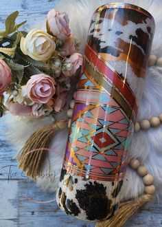 a vase sitting on top of a white fur rug next to flowers and other items