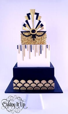 a three tiered cake with gold and black decorations on the top, sitting on a blue stand