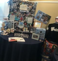 a man standing next to a table covered in pictures and memorabilia, with other items on it