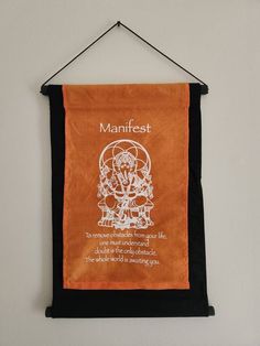 an orange banner hanging on a wall with the words manifist written below it